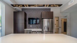 Een moderne keuken met een groot eiland, donkere houten kastjes, een ingebouwde televisie en roestvrijstalen apparatuur.