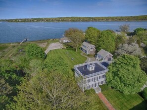 A large, two-story house with a well-maintained lawn and a dock extending into a lake. - Waterfront amazing views near beaches! (Eastham)