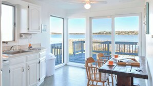 A kitchen with a view of the water, wooden deck chairs, and a table with a tray. - Waterfront amazing views near beaches! (Eastham)