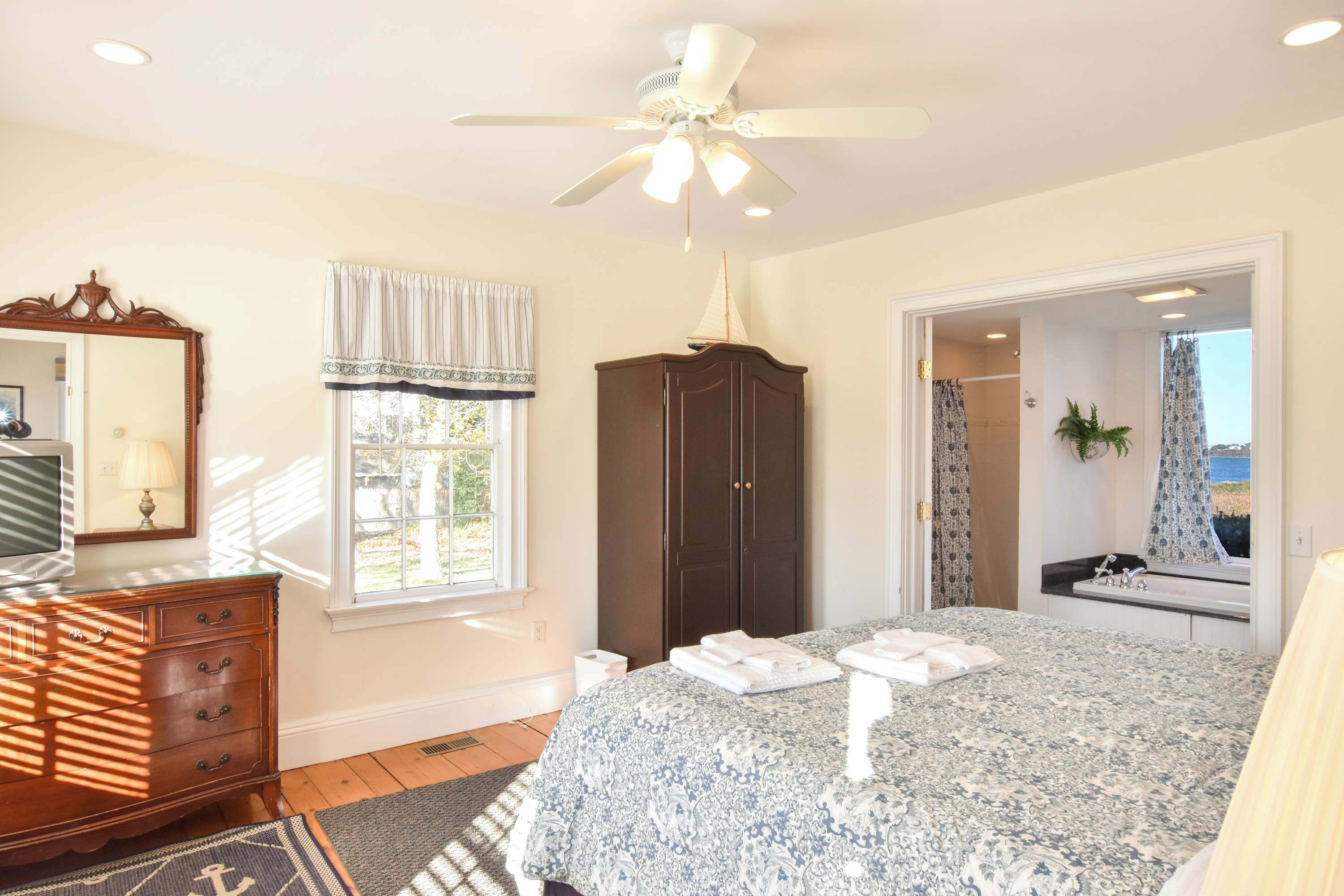 Une chambre à coucher comprenant un lit, une commode, une armoire et un ventilateur de plafond.
