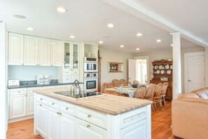 Una cocina amplia con armarios blancos, una isla central y un comedor con mesa y sillas.