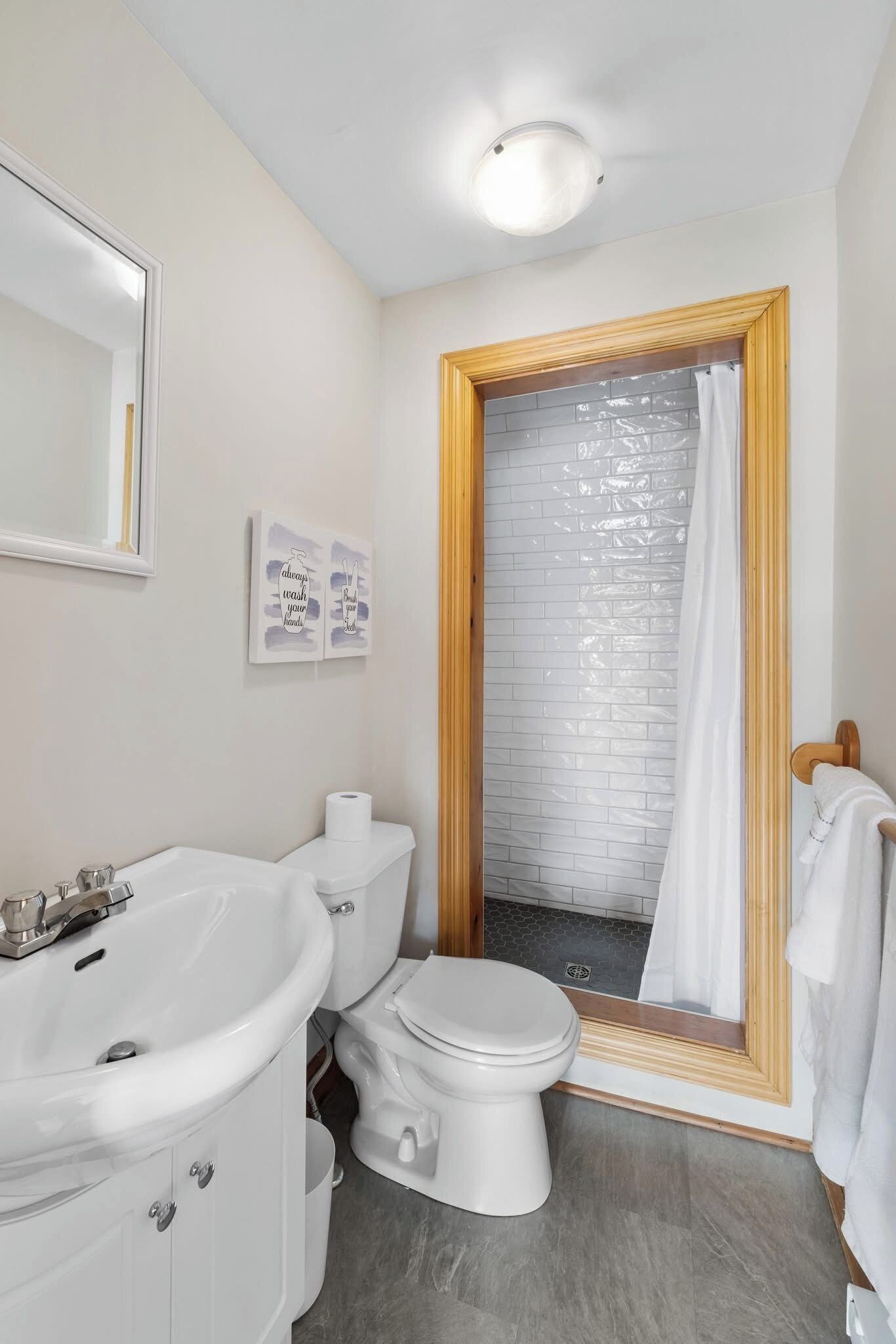 Une salle de bain avec un lavabo blanc, des toilettes et un espace douche.