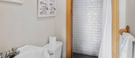 Une salle de bain avec un lavabo blanc, des toilettes et un espace douche.
