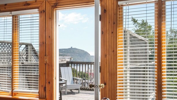 Un dormitorio con una cama grande, persianas de madera y vistas a una terraza y zona exterior.