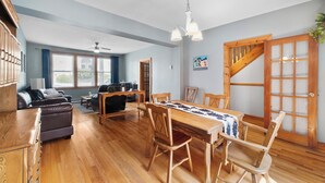 Un salón amplio con una mesa de comedor de madera, asientos cómodos y vistas al exterior a través de grandes ventanales.