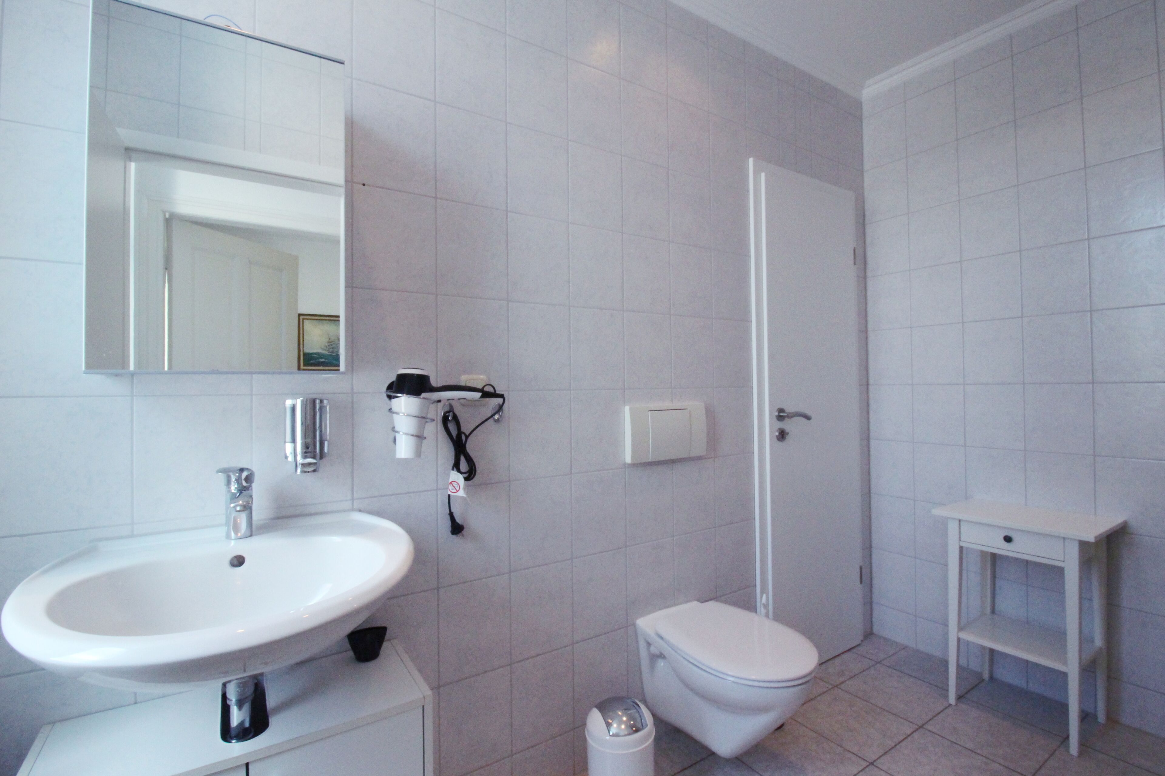 Un baño moderno con lavamanos, inodoro y ducha blancos.