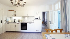 Una cocina moderna con armarios blancos, un horno negro y una mesa de comedor de madera con sillas.