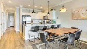 Una cocina moderna con armarios blancos, electrodomésticos de acero inoxidable y una mesa de comedor de madera con sillas negras.