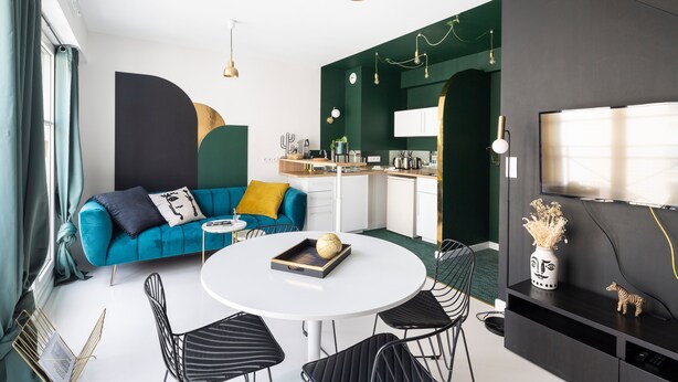 A modern living space with a blue sofa, a round dining table, and black chairs. - Jad'Or - Jolie Duplex avec parking privé (Nantes)