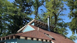 A small, light blue wooden building with a brown roof, a chimney, and a wooden bench outside. - Charming & cozy in-town retreat in the heart of New Buffalo (New Buffalo)