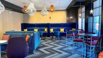 A modern lounge area with blue sofas, colorful chairs, and a patterned carpet.