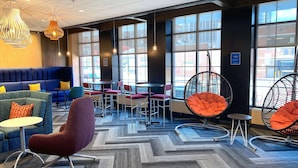 A modern lounge area with seating options including sofas, chairs, and a hanging chair. Large windows provide natural light and views of the city. - Tru By Hilton Baltimore Harbor East, MD (Baltimore)