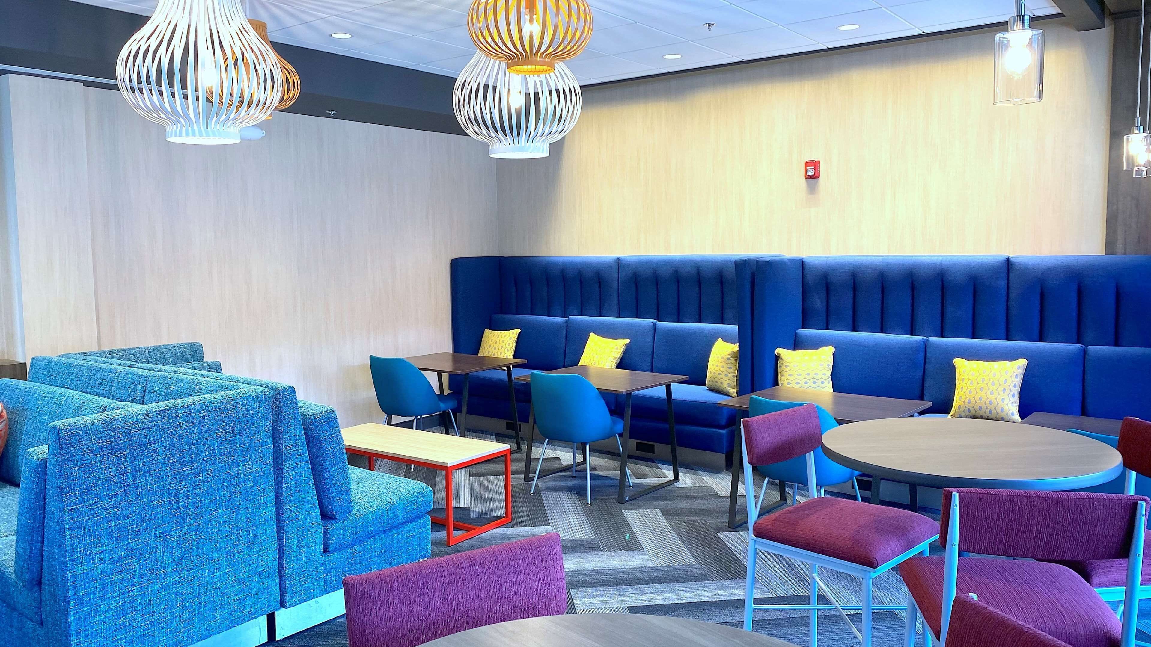 A modern lounge area with blue seating, red and blue chairs, and patterned cushions.