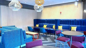 A modern lounge area with blue seating, red and blue chairs, and patterned cushions. - Tru By Hilton Baltimore Harbor East, MD (Baltimore)