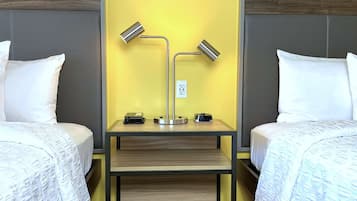 Ein Hotelzimmer mit zwei Betten, einem Nachttisch mit Lampe, Telefon und Steckdose.