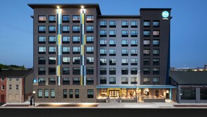 A multi-story hotel with a modern design, featuring a prominent entrance with a blue awning and a visible address number. - Tru By Hilton Baltimore Harbor East, MD (Baltimore)