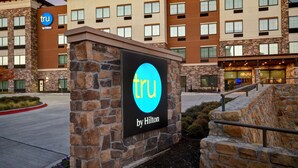 A hotel sign with the logo "tru by Hilton" and a stone wall. - Tru By Hilton Rockwall Dallas, TX (Rockwall)