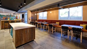 A modern restaurant interior with a central island, multiple seating options, and large windows providing natural light. - Tru By Hilton Rockwall Dallas, TX (Rockwall)