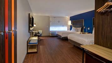 A hotel room with two beds, a desk, a chair, a TV, and a window with a view.
