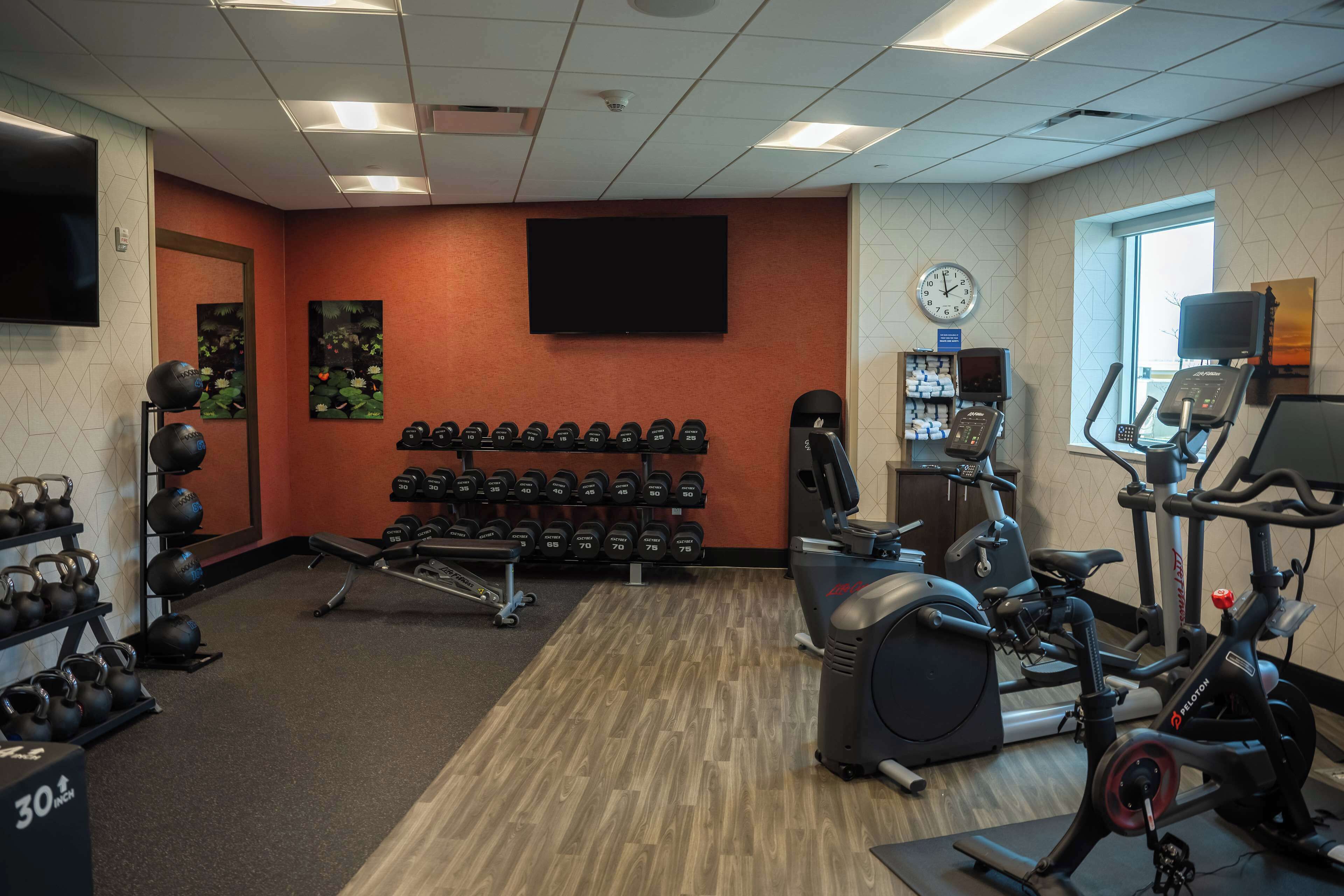 A gym with weightlifting equipment, treadmills, and a clock on the wall.
