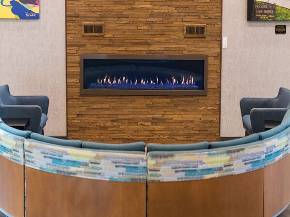 A reception area with a stone wall, a fireplace, and two blue chairs.