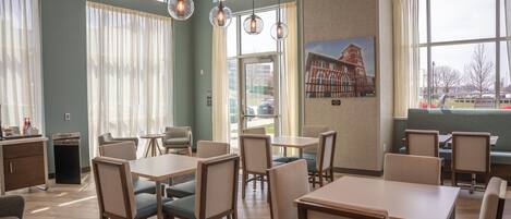 Un restaurant avec des tables et des chaises, une poubelle et une fenêtre donnant sur l’extérieur.