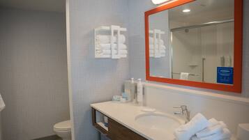 Un baño con un lavabo blanco, un espejo de marco rojo y un perchero con toallas dobladas.