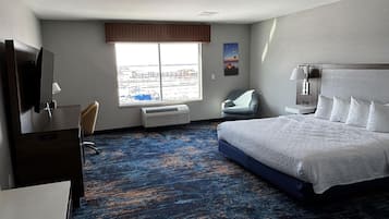 Une chambre d’hôtel avec un grand lit, un bureau, une chaise, une télévision et une fenêtre donnant sur la ville.