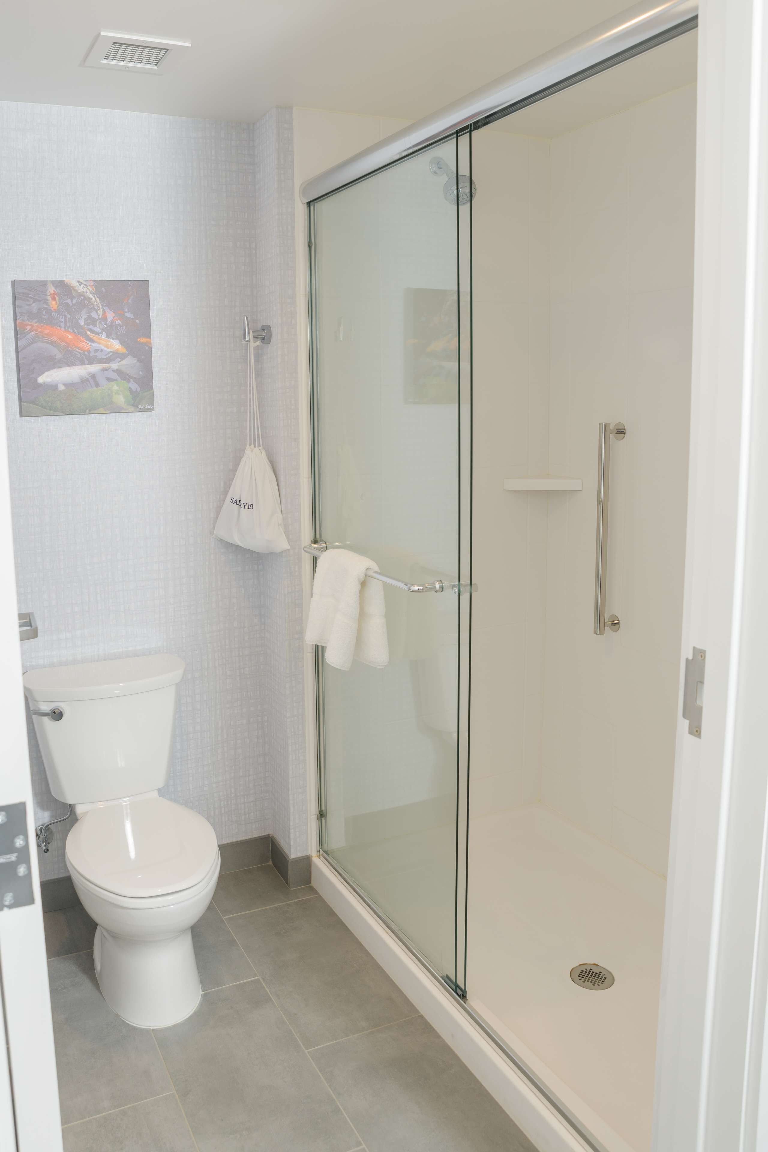 Une salle de bain équipée de toilettes, d’une douche à parois de verre et d’un porte-serviettes.