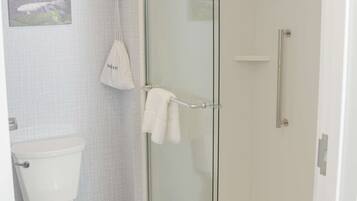 Une salle de bain équipée de toilettes, d’une douche à parois de verre et d’un porte-serviettes.