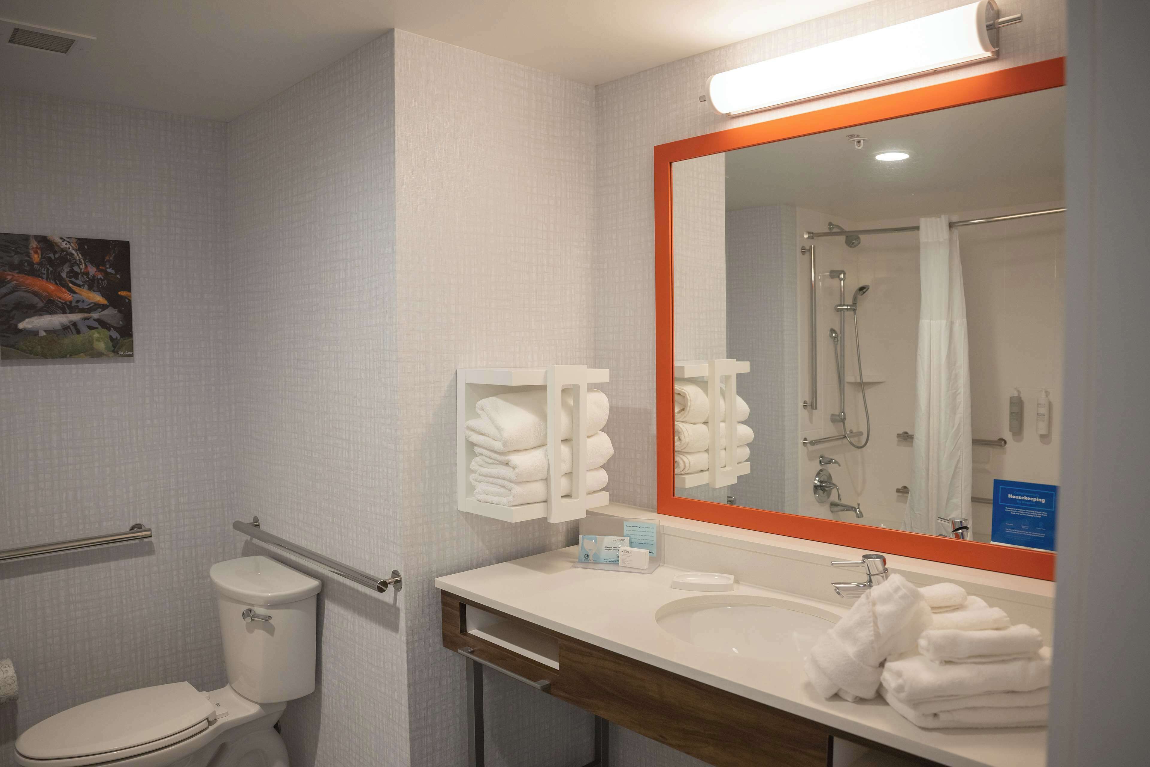 Une salle de bain équipée de toilettes, d’un lavabo et d’une douche. On y trouve des serviettes et un miroir.