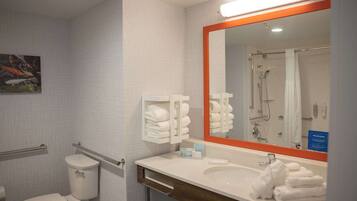 Une salle de bain équipée de toilettes, d’un lavabo et d’une douche. On y trouve des serviettes et un miroir.