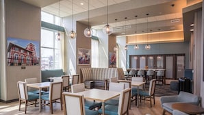 A modern hotel lobby with seating areas, tables, and artwork on the walls. - Hampton Inn & Suites Erie Bayfront (Erie)