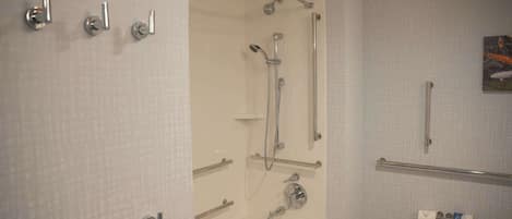 A bathroom with a bathtub, a toilet, and a shower with grab bars.