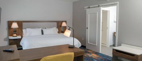 Een hotelkamer met een bed, twee bedlampen, een bureau, een stoel en een badkamer met douche en toilet.