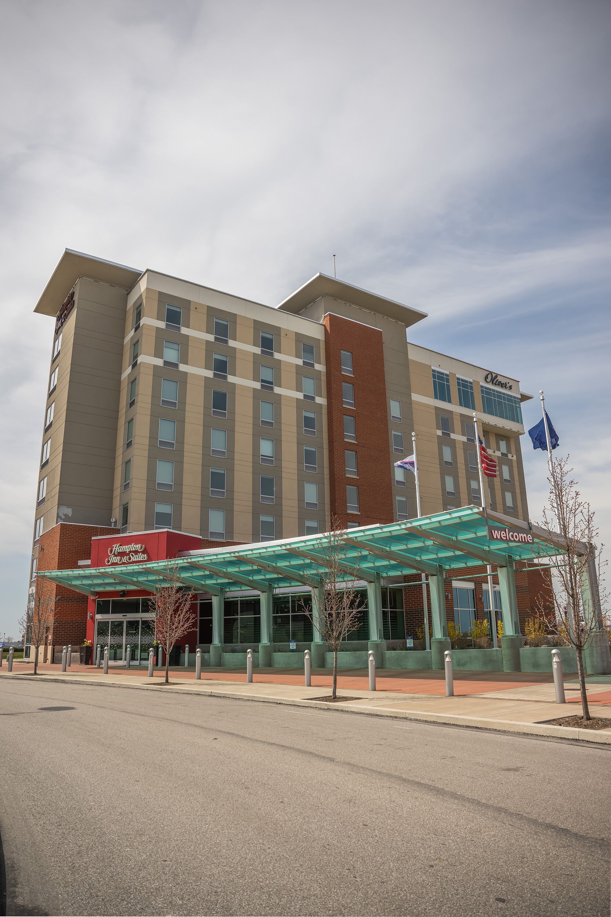 A hotel with a modern design, featuring a prominent entrance with a glass canopy and a sign that reads "Welcome."