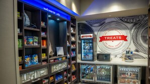 A snack and treat display area with shelves stocked with various snacks and a refrigerated section. - Hampton Inn & Suites Erie Bayfront (Erie)