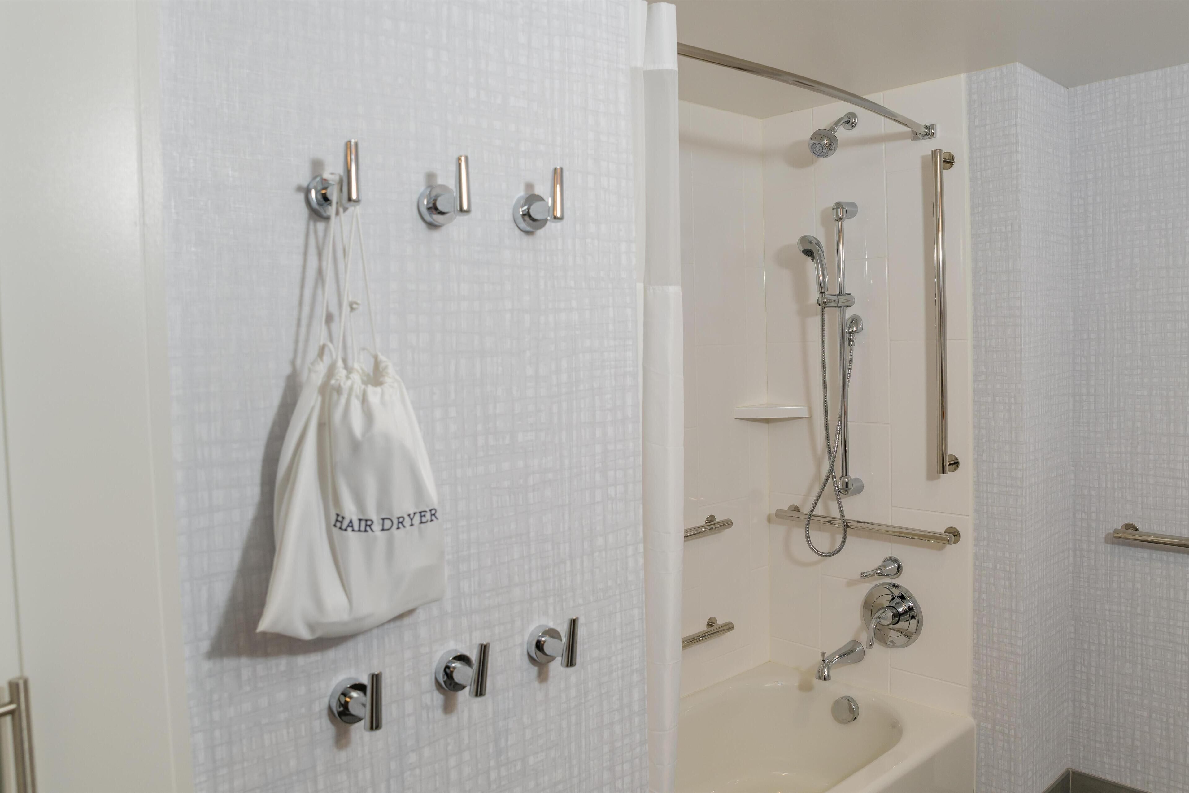 A bathroom with a shower, a bathtub, and a towel hanging on the wall.