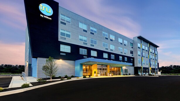 A modern hotel building with a prominent 'tru by Hilton' sign, large windows, and a covered entrance area. - Tru by Hilton Grantville, PA (Grantville)