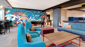 A vibrant lobby with a colorful mural, seating areas, and a pool table. - Tru by Hilton Grantville, PA (Grantville)