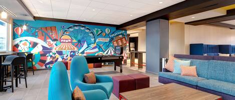 Un vestíbulo vibrante con un mural colorido, zonas de estar y una mesa de billar.