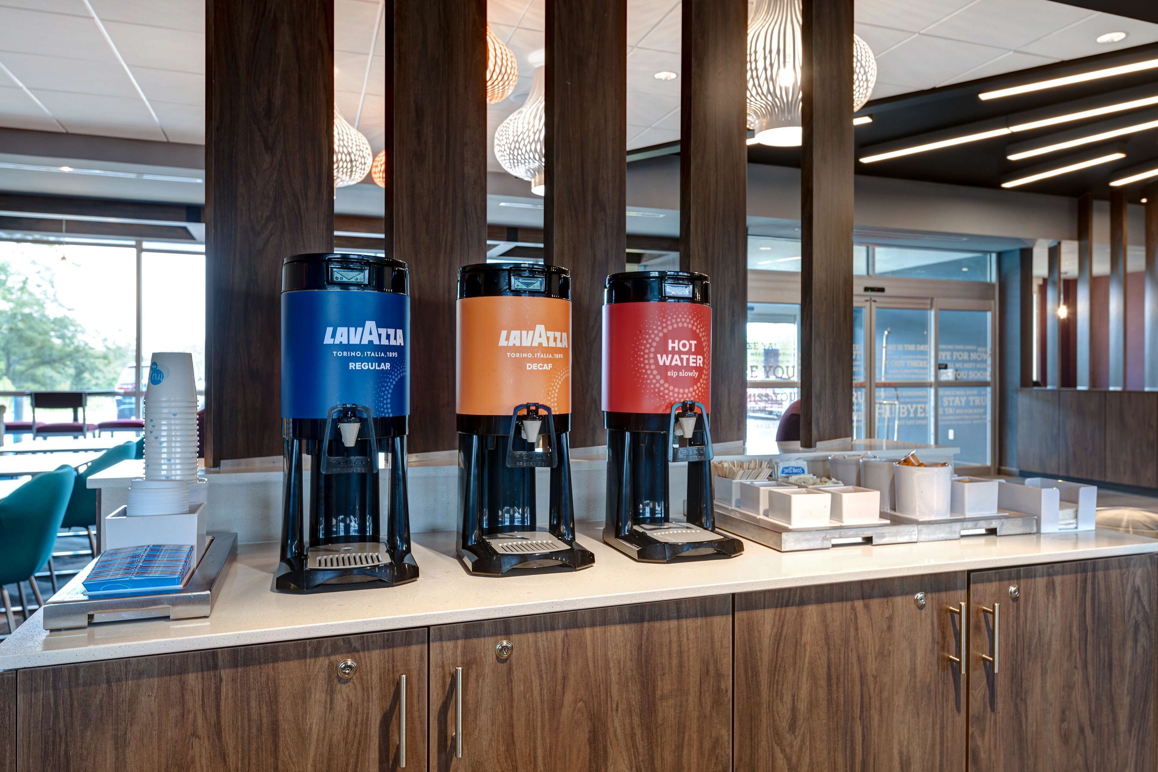 A coffee station with three dispensers labeled "Lavazza" and "Hot Water."