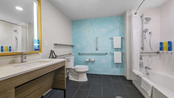 A modern bathroom with a white sink, toilet, and bathtub. There is a blue patterned wall and a mirror with a yellow frame.