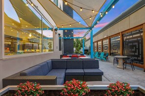 An outdoor seating area with a sofa, chairs, and tables, under a canopy with string lights. - Tru By Hilton Lathrop, CA (Lathrop)