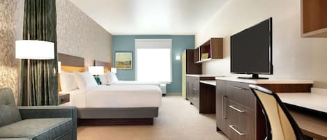 Ein Hotelzimmer mit Bett, Sofa, Schreibtisch mit Stuhl, Fernseher und Fenster.
