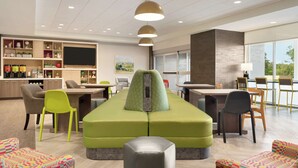 A modern lounge area with seating, a bar, and a large window providing natural light. - Home2 Suites by Hilton Ephrata (Ephrata)
