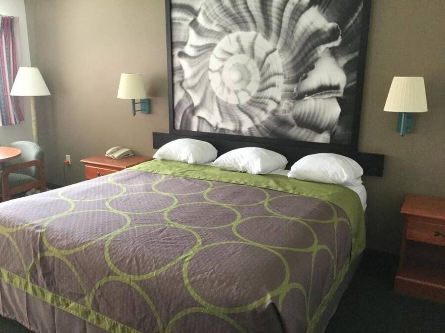 A hotel room with a large bed, two bedside lamps, a telephone, and a wall-mounted artwork.