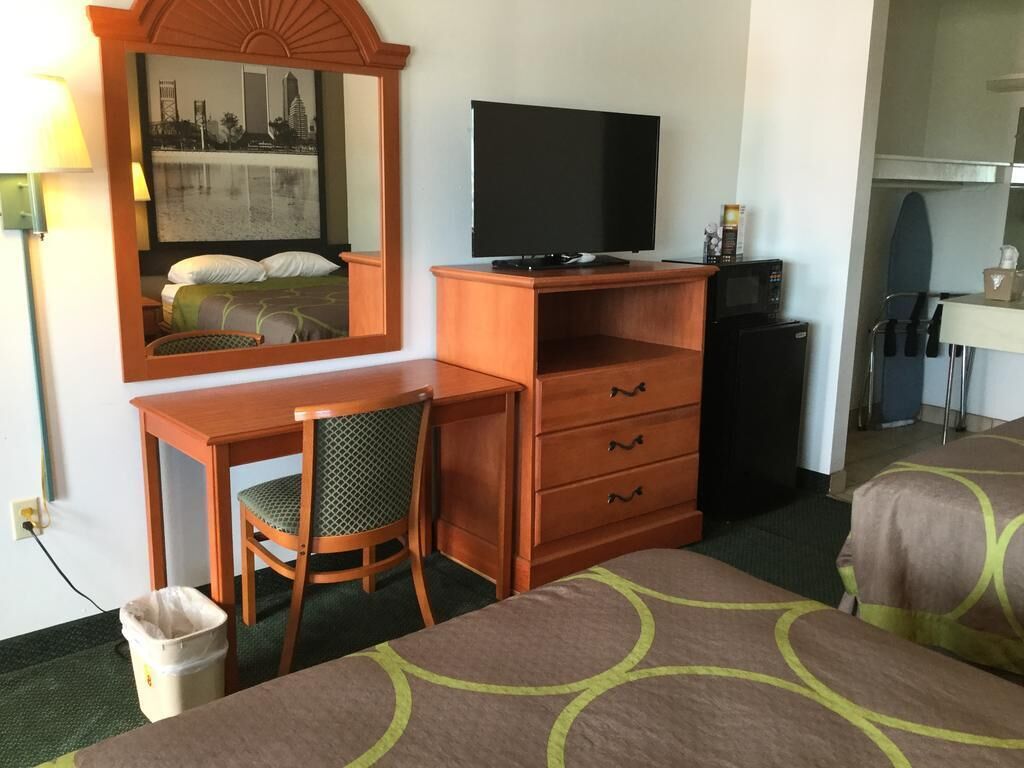 Hotelkamer met een bed, bureau met stoel, televisie, kleine koelkast en prullenbak.