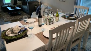 A dining area with a table set for two, featuring a bottle of wine, glasses, and a decorative lantern.