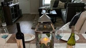 A dining table set with plates, wine glasses, and bottles, surrounded by a cozy living room with a sofa and a decorative lantern.